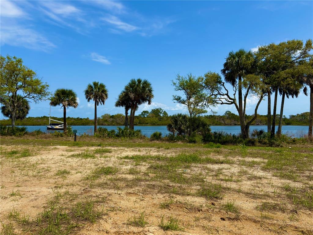 A grassy, sandy lot overlooks a body of water with palm trees and a sailboat — 140 CORONADO ROAD, FLAGLER BEACH, FL