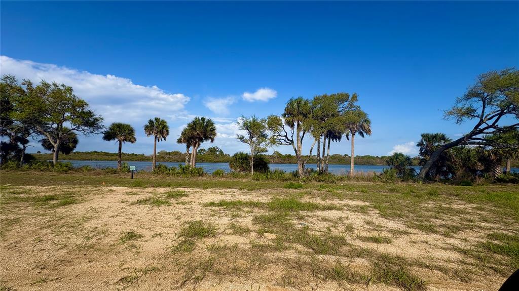 A vacant, grassy lot overlooks a body of water lined with palm and oak trees — 140 CORONADO ROAD, FLAGLER BEACH, FL