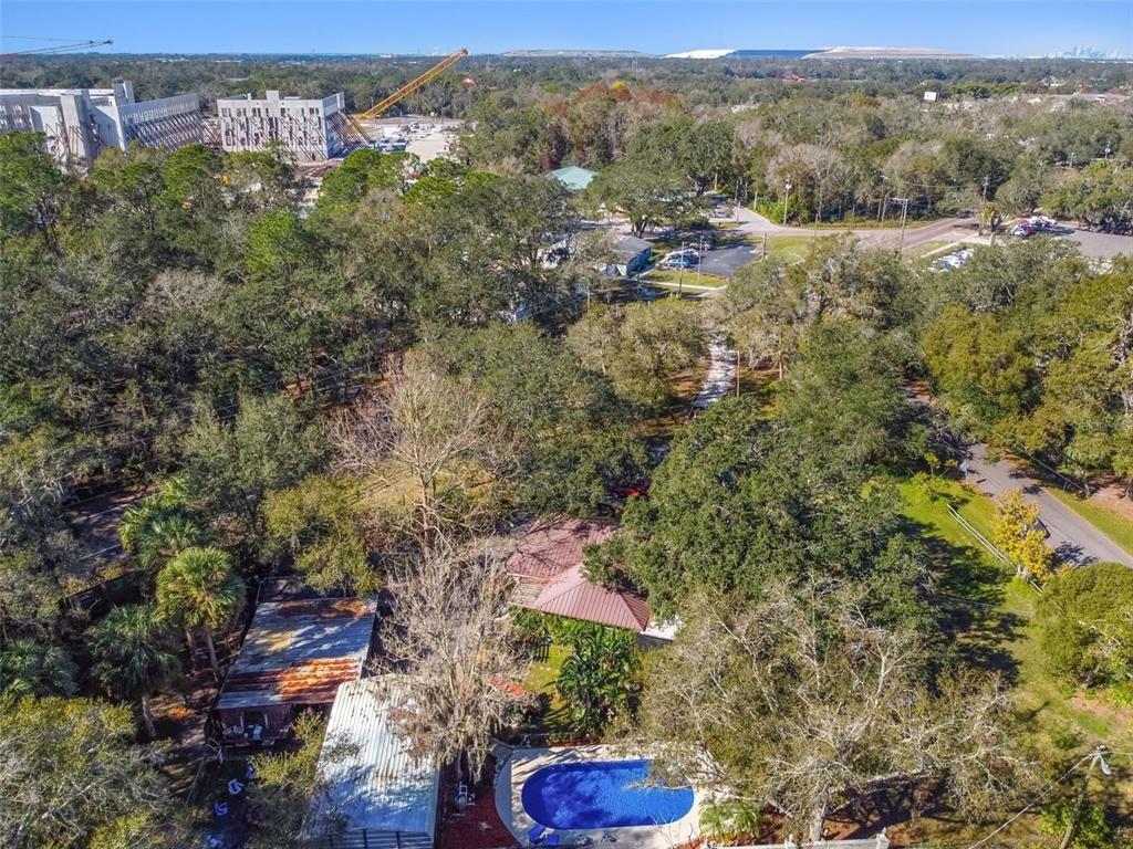 An aerial view shows a house with a pool, outbuildings, and surrounding wooded property — 10901 MCMULLEN LOOP, RIVERVIEW, FL