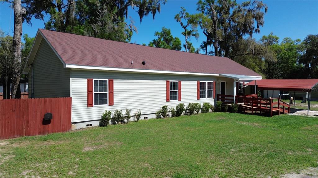 A single-story house with light siding, red shutters, and a wooden deck entrance — 28477 SENTINEL STREET, NOBLETON, FL