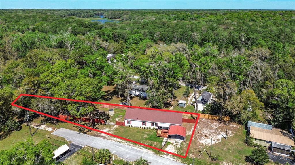 An aerial view shows a single-story house with a red roof and carport on a lot — 28477 SENTINEL STREET, NOBLETON, FL