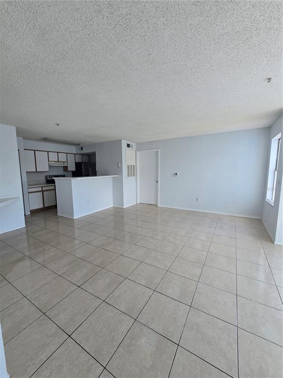 An open-concept living area features light-colored tile flooring, a kitchen with white cabinets, and a breakfast bar — 2214 GRAND CAYMAN COURT UNIT 1516, KISSIMMEE, FL