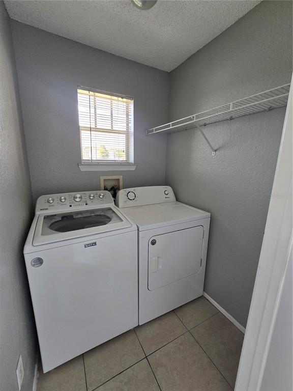 A laundry room features white appliances, gray walls, tile flooring, and a wire wall shelf — 2214 GRAND CAYMAN COURT UNIT 1516, KISSIMMEE, FL