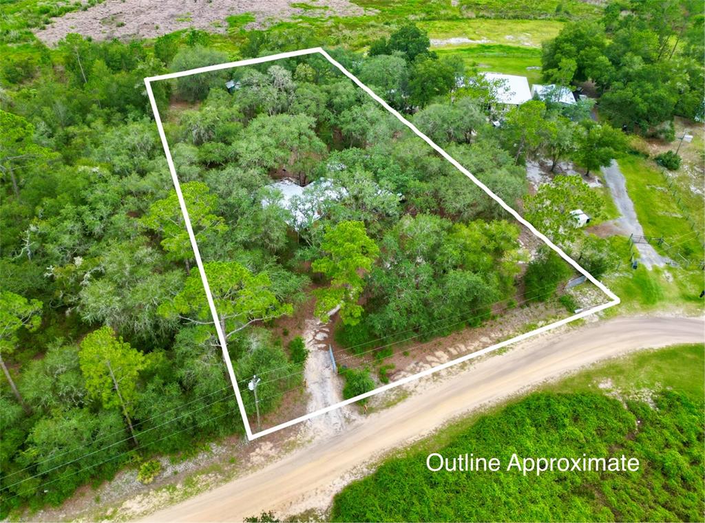 An aerial view shows a wooded residential lot outlined in white next to a road — 5816 BRYCE STREET, KEYSTONE HEIGHTS, FL