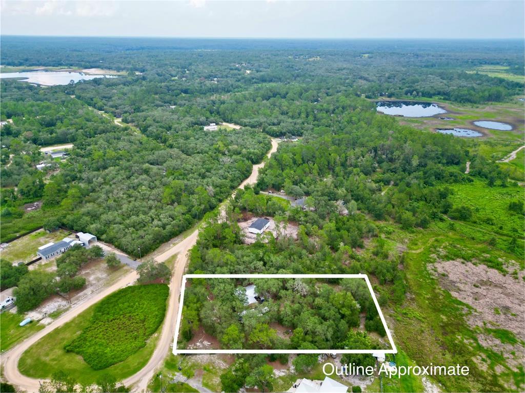 An aerial view shows a wooded lot with a house outlined in white — 5816 BRYCE STREET, KEYSTONE HEIGHTS, FL