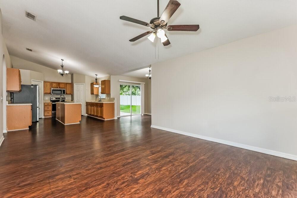 An open-concept living area features dark wood-look flooring, a ceiling fan, and a kitchen — 436 FISH HAWK DRIVE, WINTER HAVEN, FL