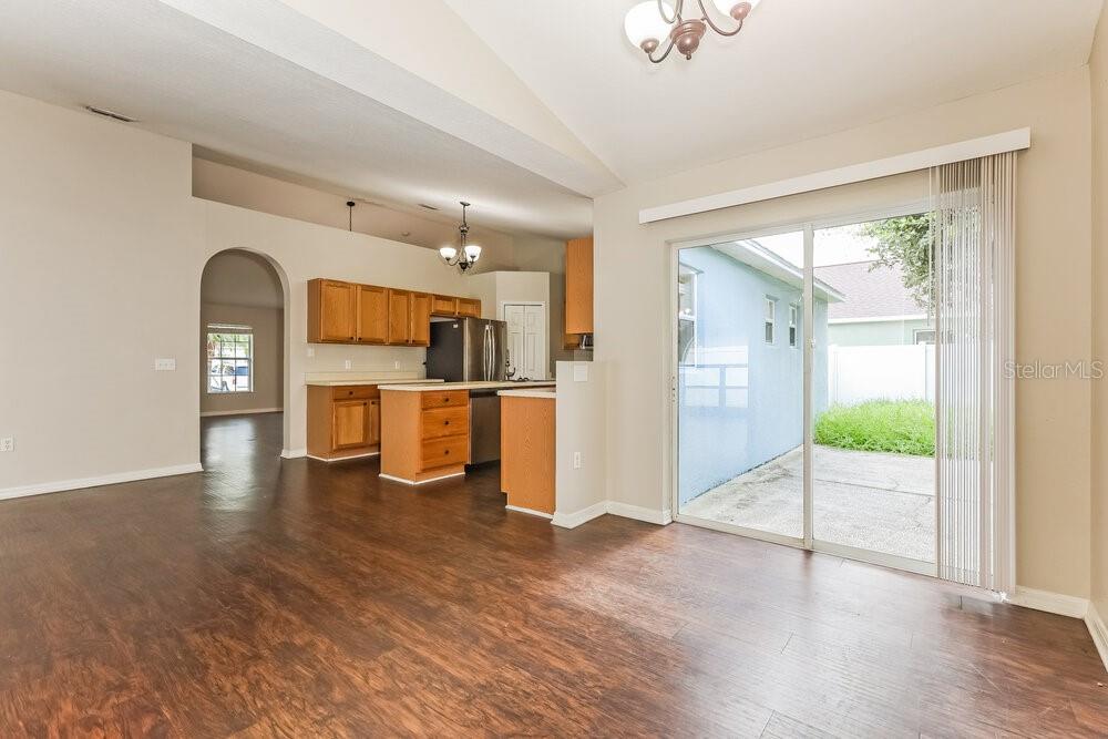An open-concept living area features dark wood floors, a kitchen with wood cabinets, and sliding doors — 436 FISH HAWK DRIVE, WINTER HAVEN, FL