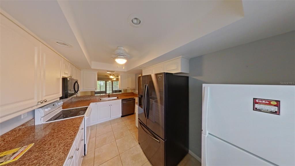 A kitchen features white cabinets, granite countertops, a dark refrigerator, and a white refrigerator — 4602 LAFAYETTE AVENUE, SEBRING, FL