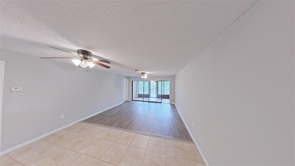 A living area with tile flooring in the foreground and wood-look flooring in the back — 4602 LAFAYETTE AVENUE, SEBRING, FL