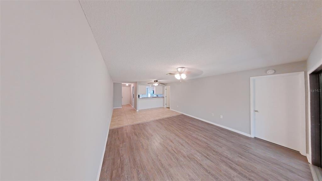 A living room with wood-look flooring transitions to a tiled kitchen area with ceiling fans — 4602 LAFAYETTE AVENUE, SEBRING, FL