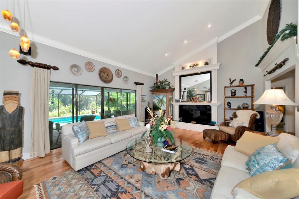 A living room features a fireplace, a glass-topped coffee table, and sliding doors to a pool — 4737 STONE RIDGE TRAIL, SARASOTA, FL