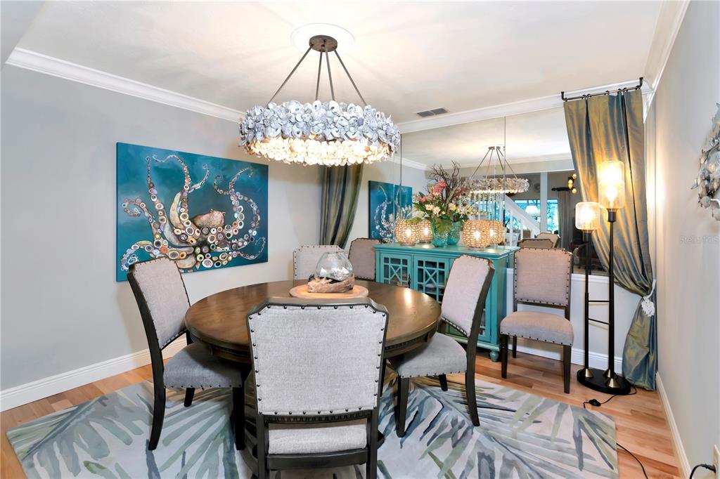 A dining room features a round wooden table, upholstered chairs, a chandelier, and octopus artwork — 4737 STONE RIDGE TRAIL, SARASOTA, FL