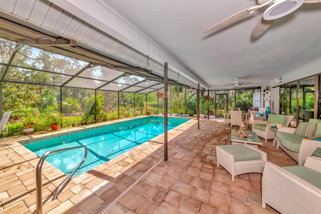 A screened-in patio features a rectangular swimming pool, brick pavers, and outdoor furniture — 4737 STONE RIDGE TRAIL, SARASOTA, FL
