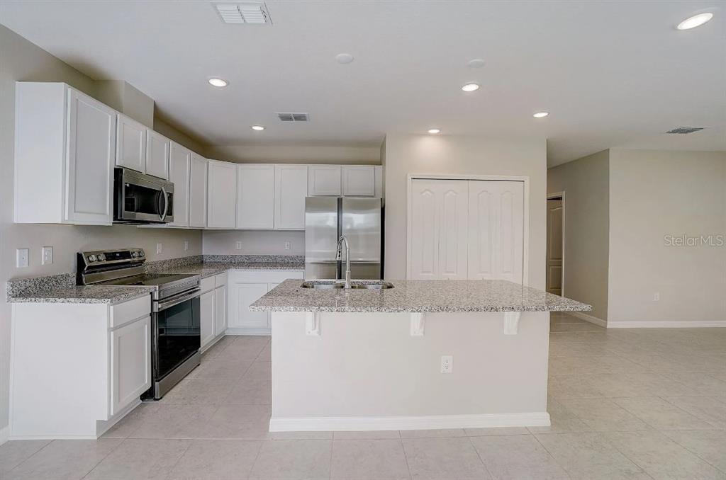 A kitchen features white cabinets, granite countertops, stainless steel appliances, and a central island — 16849 NW 176TH WAY, ALACHUA, FL