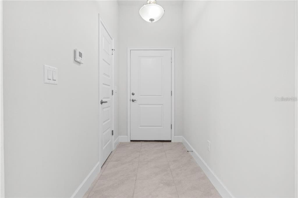 A white-walled entryway features a tiled floor, a ceiling light, and a white door — 39 RIVERINA DRIVE, PALM COAST, FL