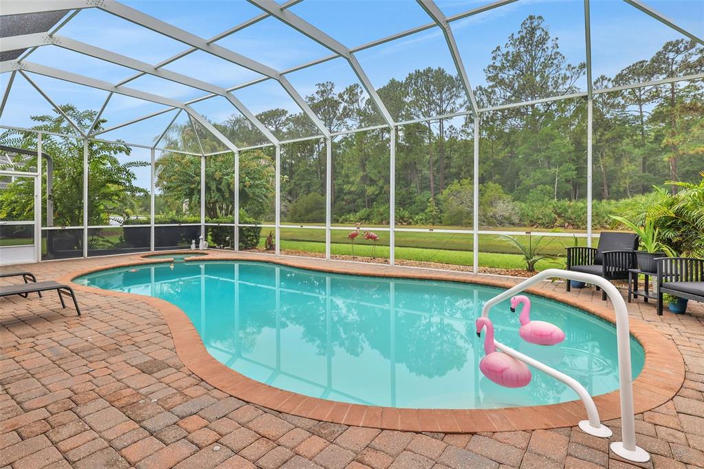 A screened-in swimming pool with a brick paver deck overlooks a wooded backyard — 1244 HARWICK LANE, ORMOND BEACH, FL