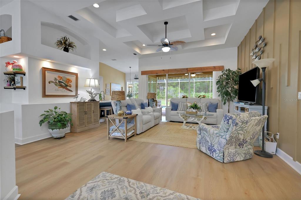 A bright living room features a coffered ceiling, light wood flooring, and coastal-themed decor — 1244 HARWICK LANE, ORMOND BEACH, FL