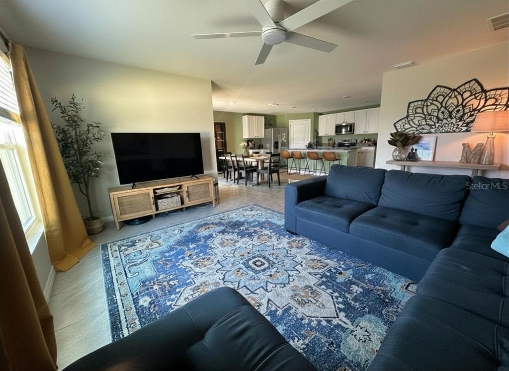 A covered concrete patio features a small stone-inlaid walkway, outdoor furniture, and potted plants — 6830 SE 3RD LOOP, OCALA, FL