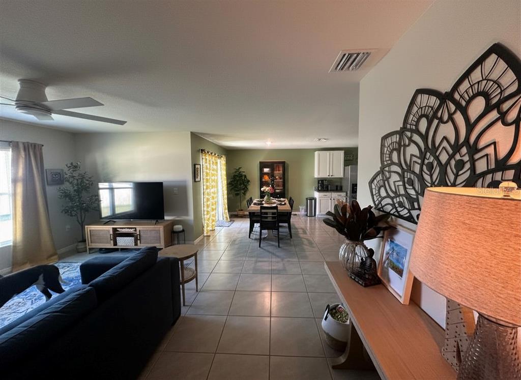 A covered patio overlooks a fenced backyard with a fire pit and colorful outdoor seating — 6830 SE 3RD LOOP, OCALA, FL