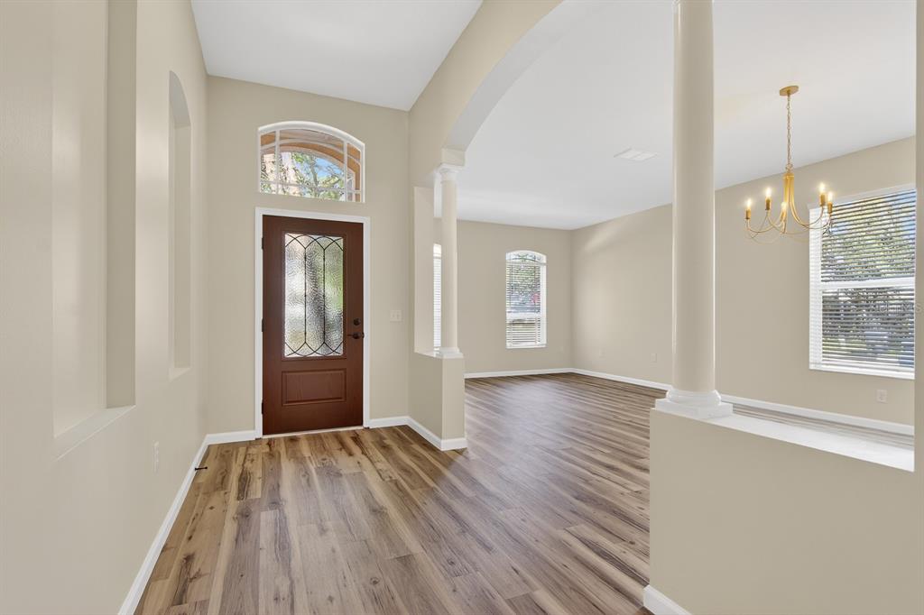 An entryway with wood-look flooring, a brown front door, and white columns leading to a room — 6002 MARTINGLADE PLACE, LITHIA, FL
