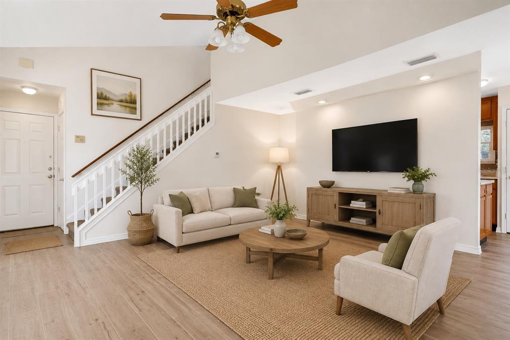 An interior view of a living room with light wood-look flooring and a staircase — 11842 ATLIN DRIVE, ORLANDO, FL
