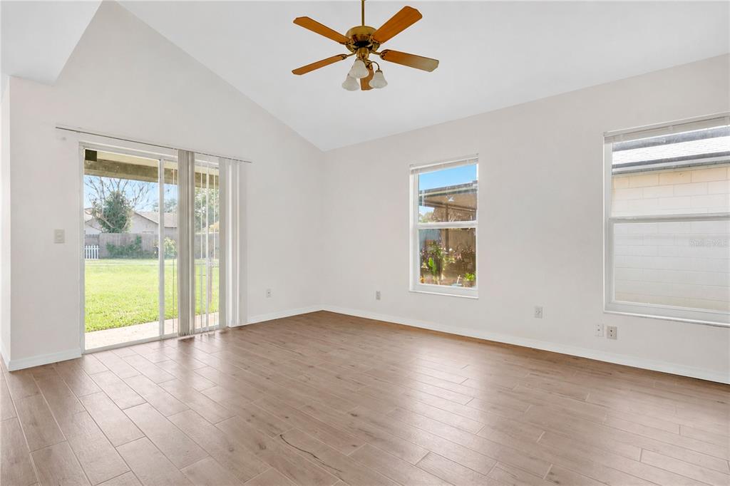 A kitchen with wood cabinets and light wood-look flooring opens into a dining area — 11842 ATLIN DRIVE, ORLANDO, FL