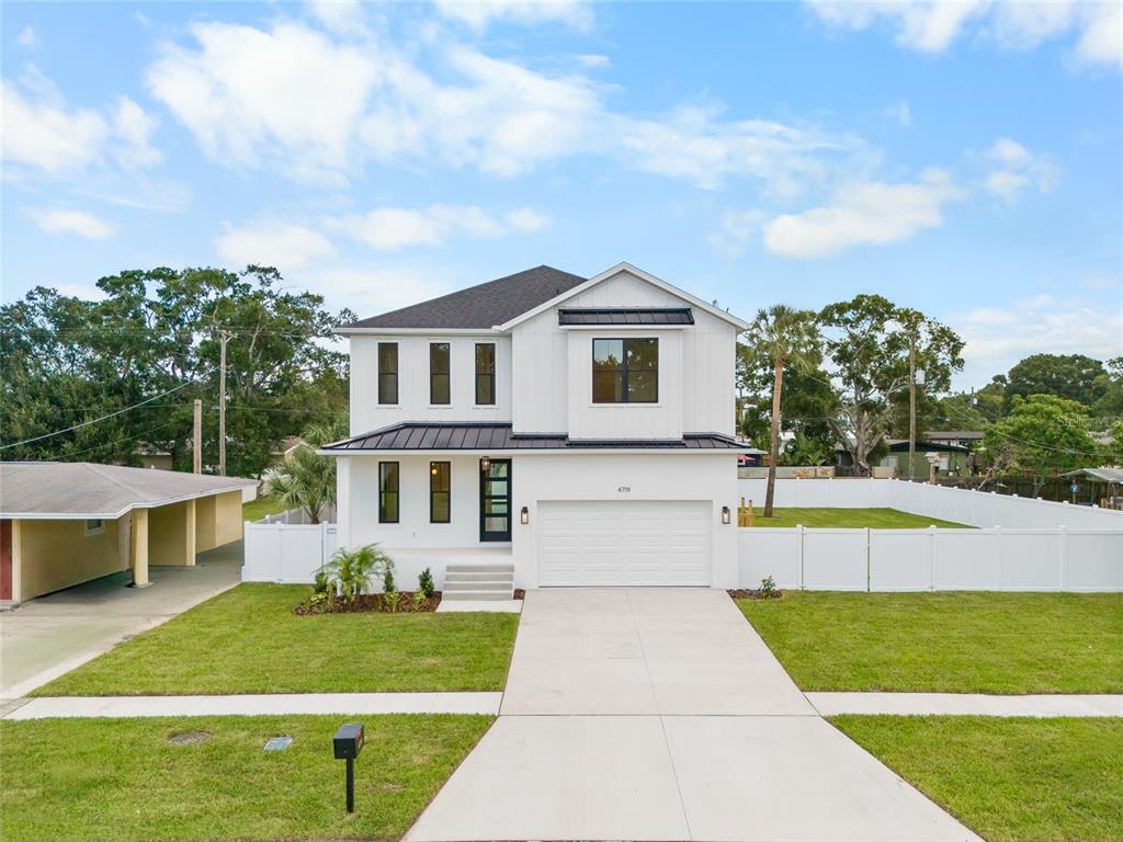 A two-story white house with a metal roof and a two-car garage at sunset — 4719 W WYOMING AVENUE, TAMPA, FL