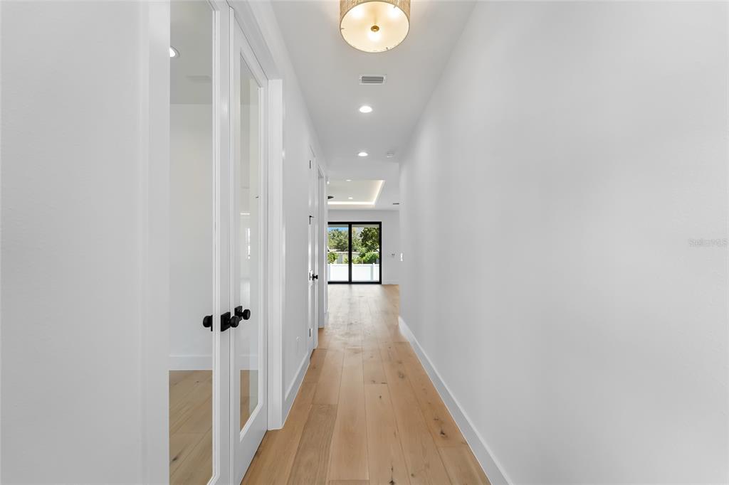 A room with light wood floors, a dark green accent wall, and a modern chandelier — 4719 W WYOMING AVENUE, TAMPA, FL