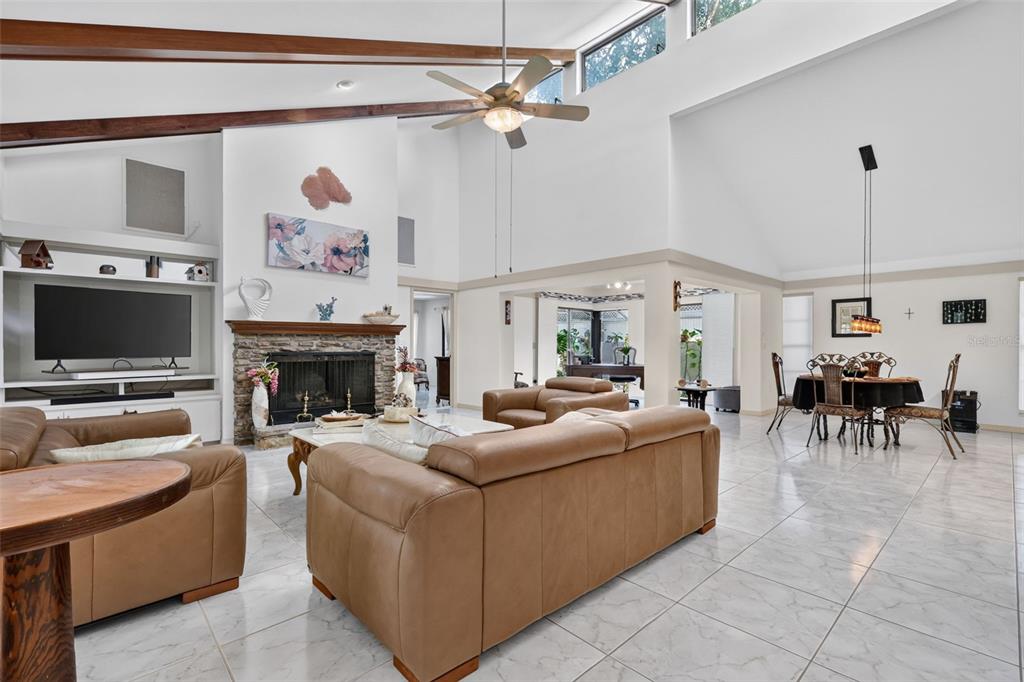 A spacious living room features a stone fireplace, vaulted ceilings, and light-colored tile flooring — 21 TOWNHILL DRIVE, EUSTIS, FL