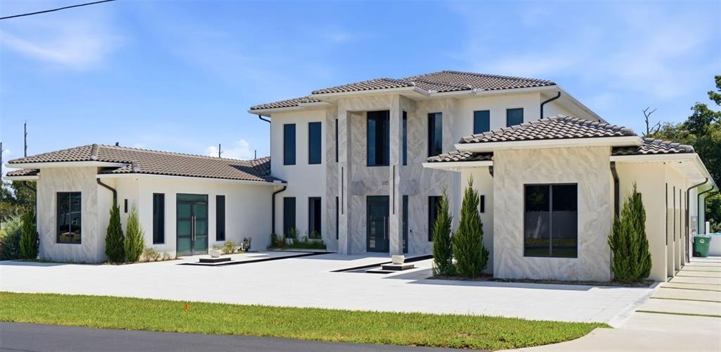 A modern two-story house with white stucco walls, stone accents, and a tiled roof — 3857 S STILLWOOD LANE, LAKE MARY, FL