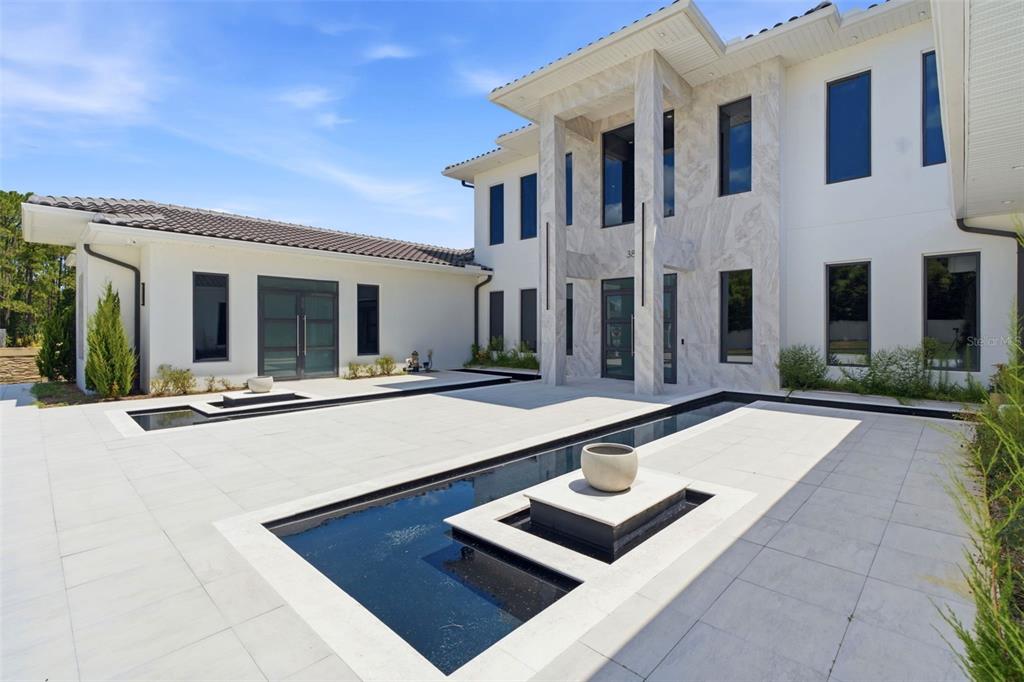A modern two-story house features a white exterior, marble entryway, and a long reflecting pool — 3857 S STILLWOOD LANE, LAKE MARY, FL