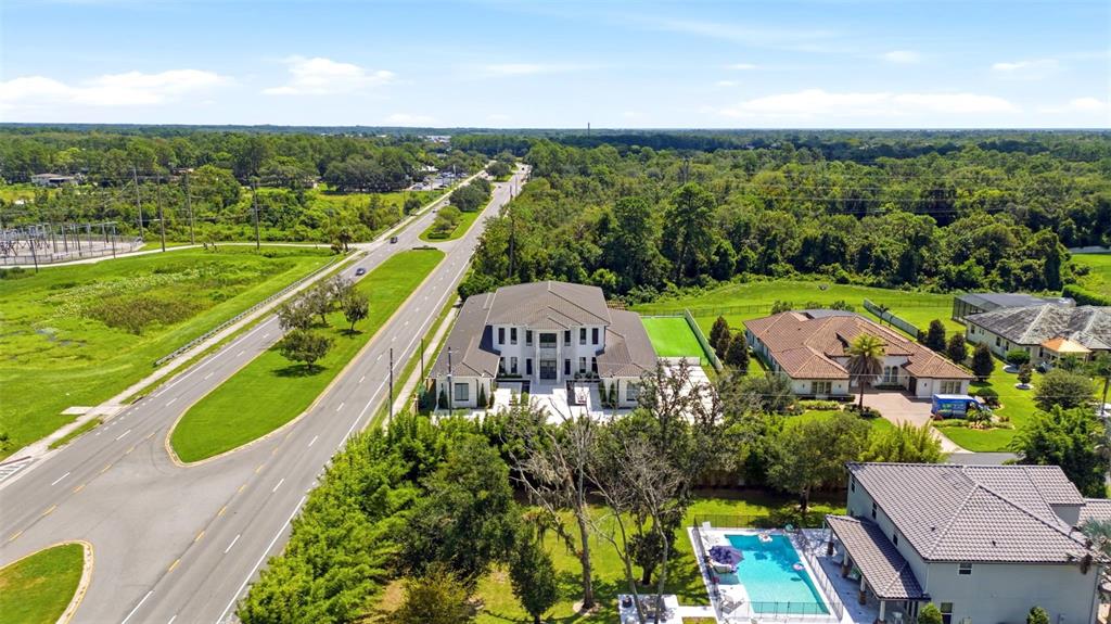 An aerial view shows a large multi-story house with a pool next to a road — 3857 S STILLWOOD LANE, LAKE MARY, FL