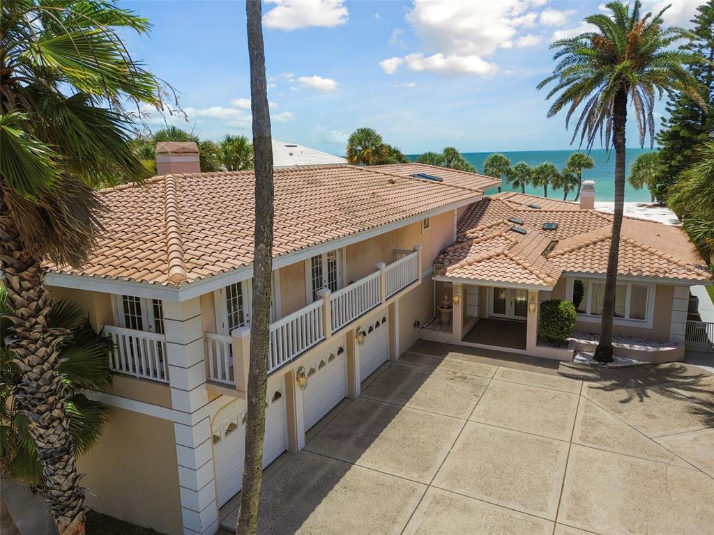 An elevated view of a two-story house with a tile roof, balconies, and a driveway — 1520 GULF BOULEVARD, BELLEAIR BEACH, FL