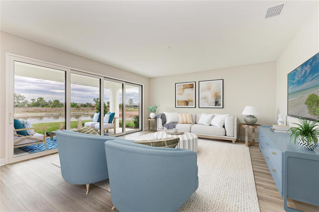 A living room features blue armchairs, a white sofa, and sliding doors overlooking a lake — 13718 HEARTWOOD WAY, PARRISH, FL