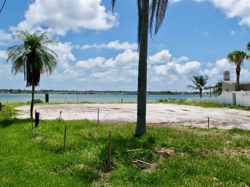 A vacant waterfront lot features sandy ground, several palm trees, and a view of water — 16003 5TH STREET E, REDINGTON BEACH, FL