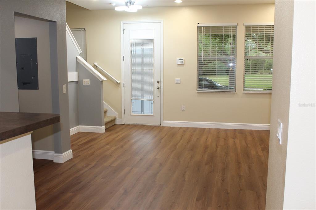 An interior view shows a room with wood-look flooring, a staircase, and a glass-paneled door — 7365 BRIGHTLAND STREET, WINDERMERE, FL