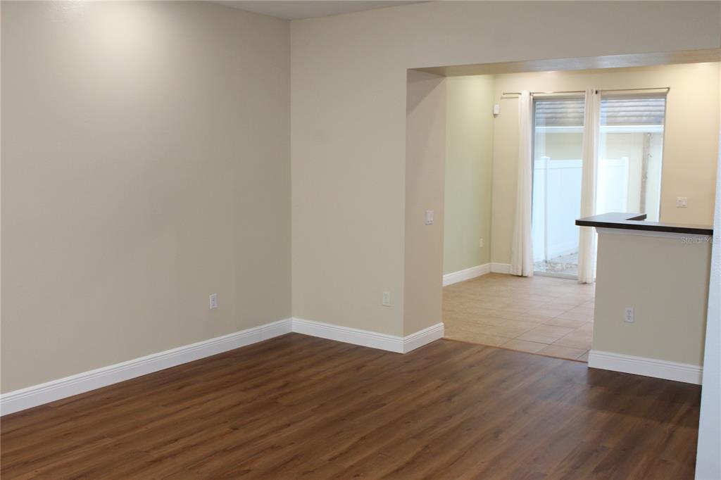 An interior view shows a living area with wood-look flooring and an adjacent tiled room — 7365 BRIGHTLAND STREET, WINDERMERE, FL