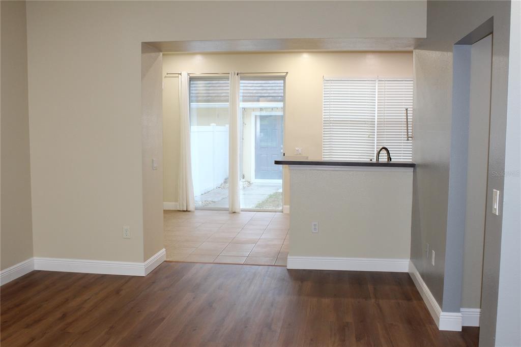 A living area with wood-look flooring leads to a tiled dining space with sliding glass doors — 7365 BRIGHTLAND STREET, WINDERMERE, FL