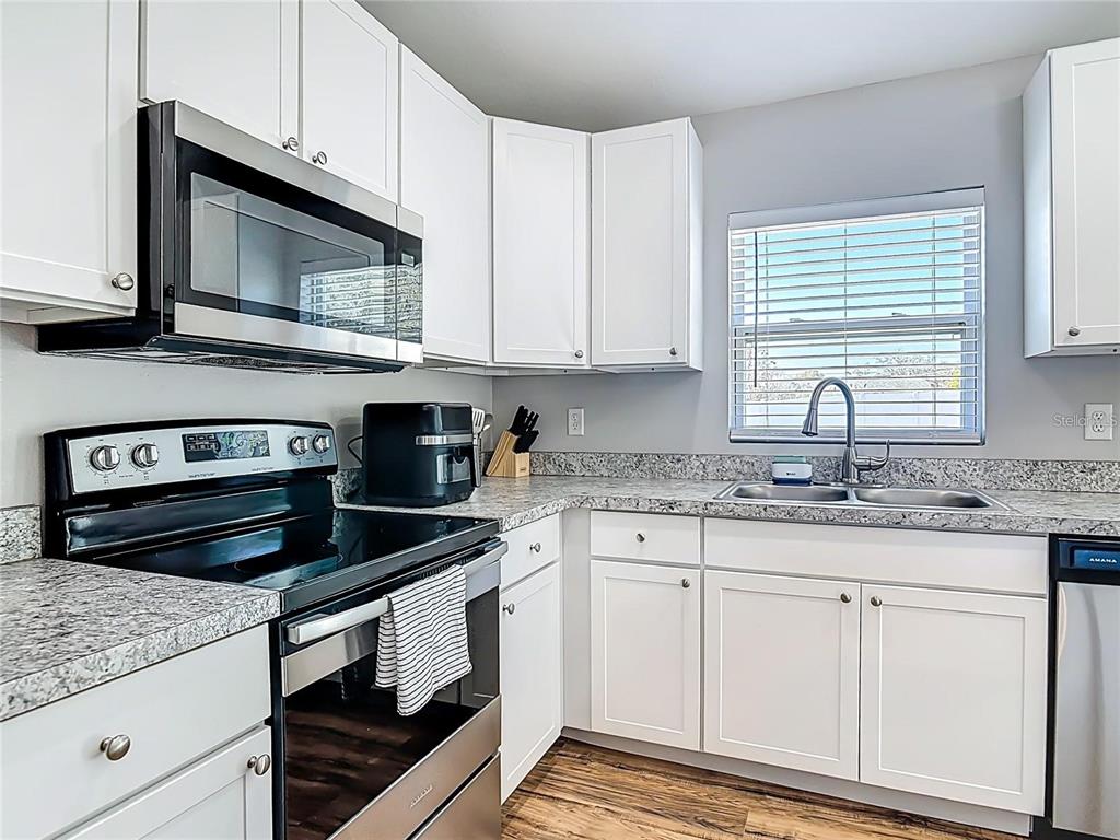 A kitchen with white cabinets, granite countertops, stainless steel appliances, and a window above the sink — 640 CHESTNUT AVENUE, ORANGE CITY, FL