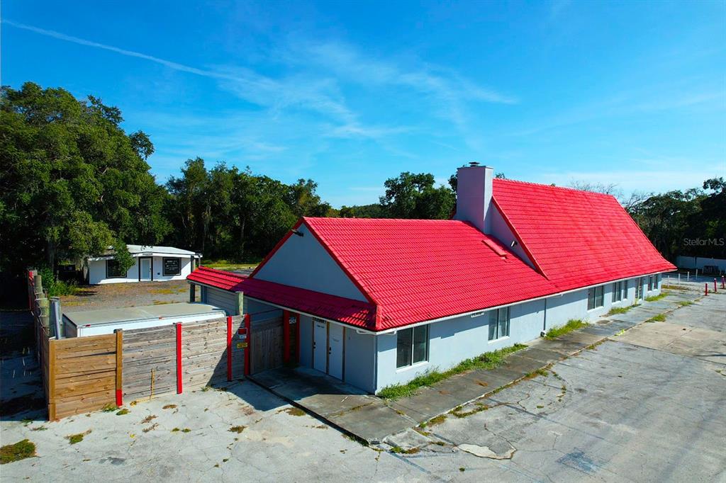 An exterior view of a light-colored commercial building with a prominent red metal roof — 4795 US-1 HIGHWAY, MIMS, FL