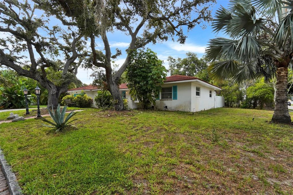 A white single-story house with a red tile roof sits on a grassy lot — 7716 DARTMOUTH AVENUE N, ST PETERSBURG, FL
