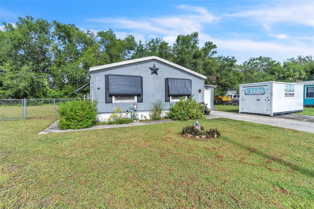 A gray single-story house with a star decoration and a storage container in the yard — 2576 LAKOTA LANE, ST CLOUD, FL