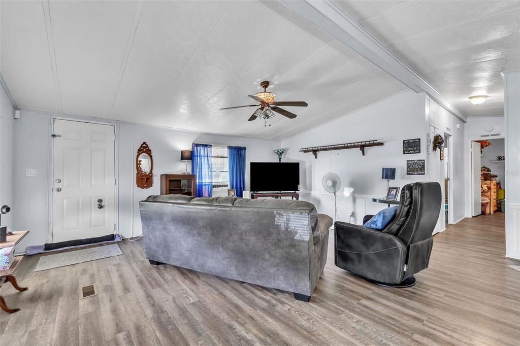 A living room features a gray sofa, a black recliner, and wood-look flooring — 2576 LAKOTA LANE, ST CLOUD, FL