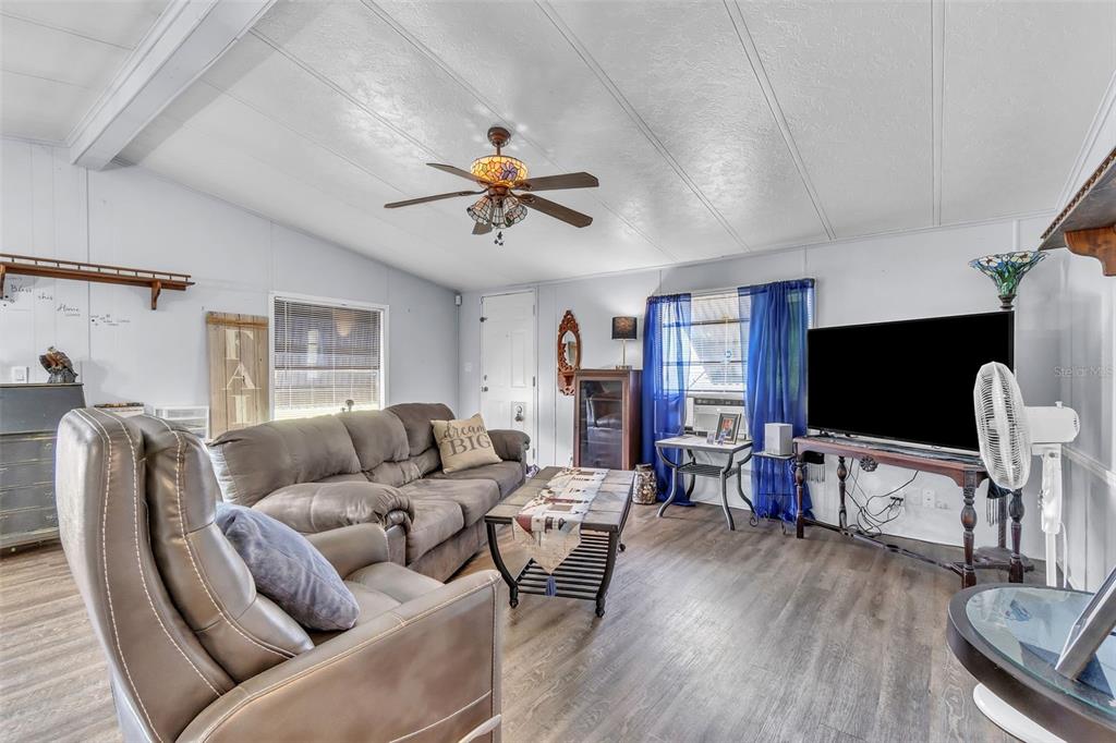 A living room features wood-look flooring, a ceiling fan, a sofa, and a television — 2576 LAKOTA LANE, ST CLOUD, FL