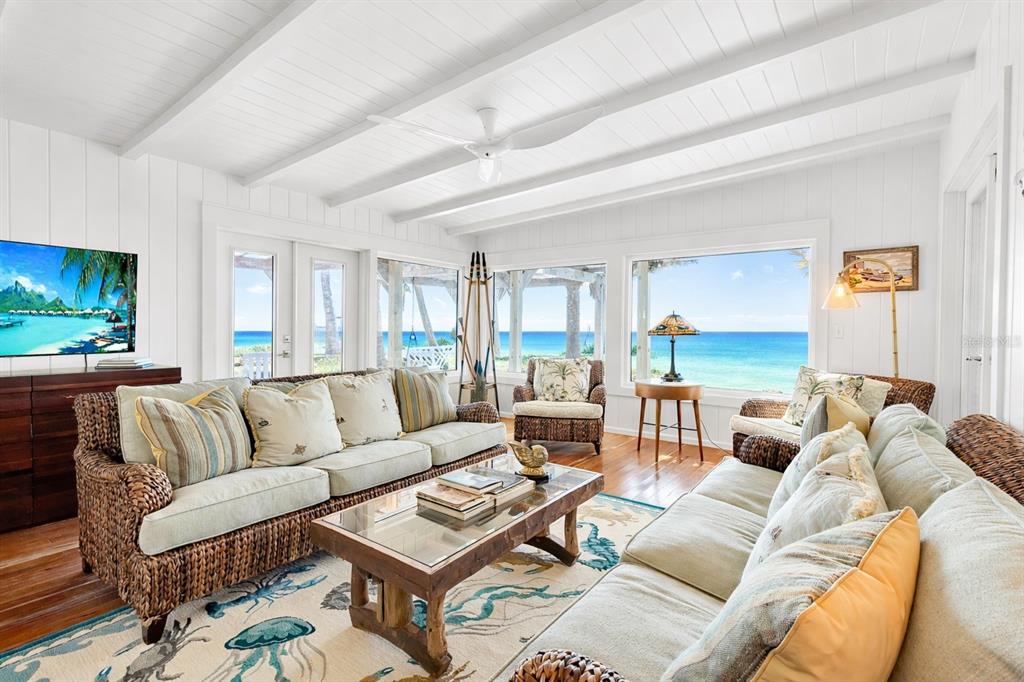 A living room with wicker furniture, a patterned area rug, and ocean views through windows — 621 CASEY KEY ROAD, NOKOMIS, FL