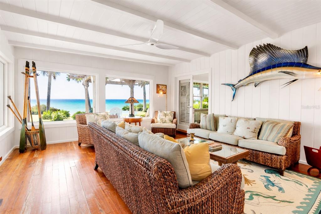 A coastal living room features wicker furniture, a large sailfish wall mount, and ocean views — 621 CASEY KEY ROAD, NOKOMIS, FL