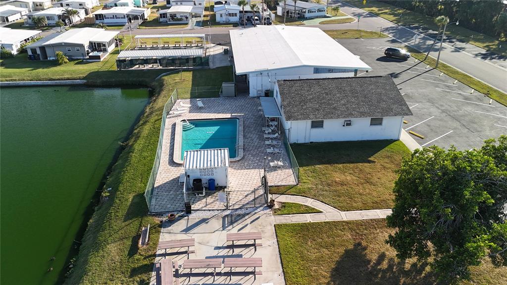 An aerial view shows a community pool, a clubhouse, and picnic tables near a pond — 306 50TH AVENUE PLAZA E, BRADENTON, FL