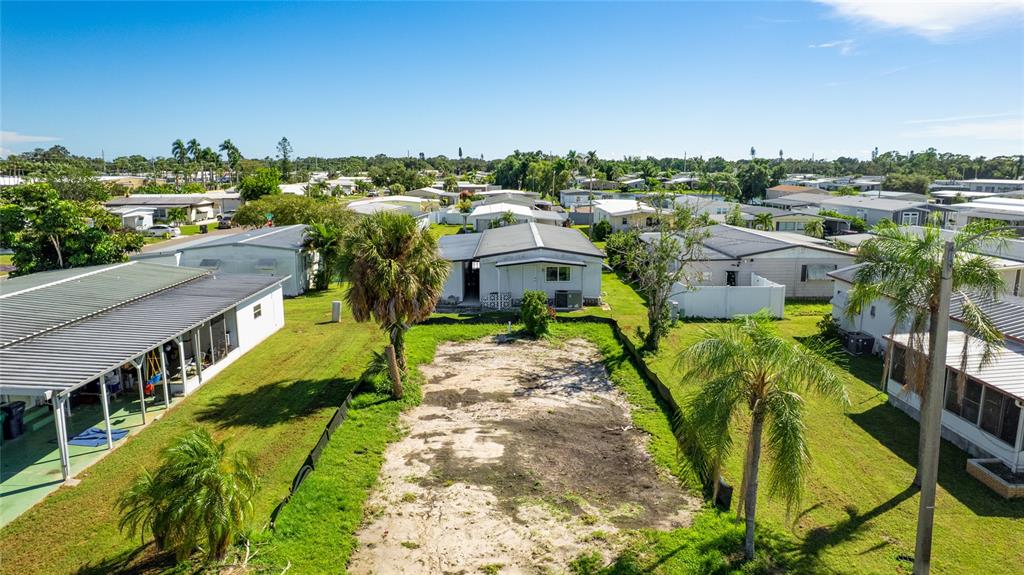 An aerial view shows a vacant, sandy residential lot situated between two manufactured homes — 306 50TH AVENUE PLAZA E, BRADENTON, FL