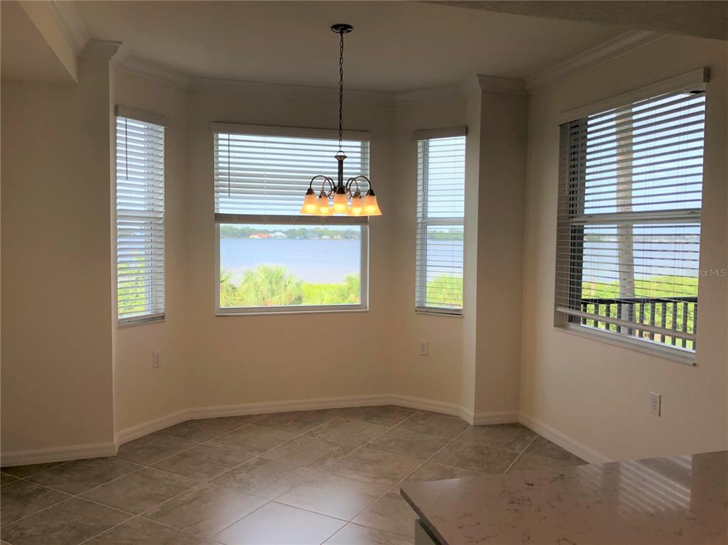 A dining nook features tile flooring, a chandelier, and large windows overlooking a body of water — 1010 TIDEWATER SHORES LOOP UNIT 206, BRADENTON, FL