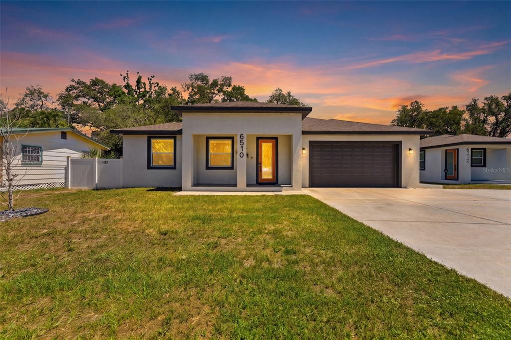 A single-story house with a flat-roofed entryway, a two-car garage, and a sunset sky — 6510 E 25TH AVENUE, TAMPA, FL